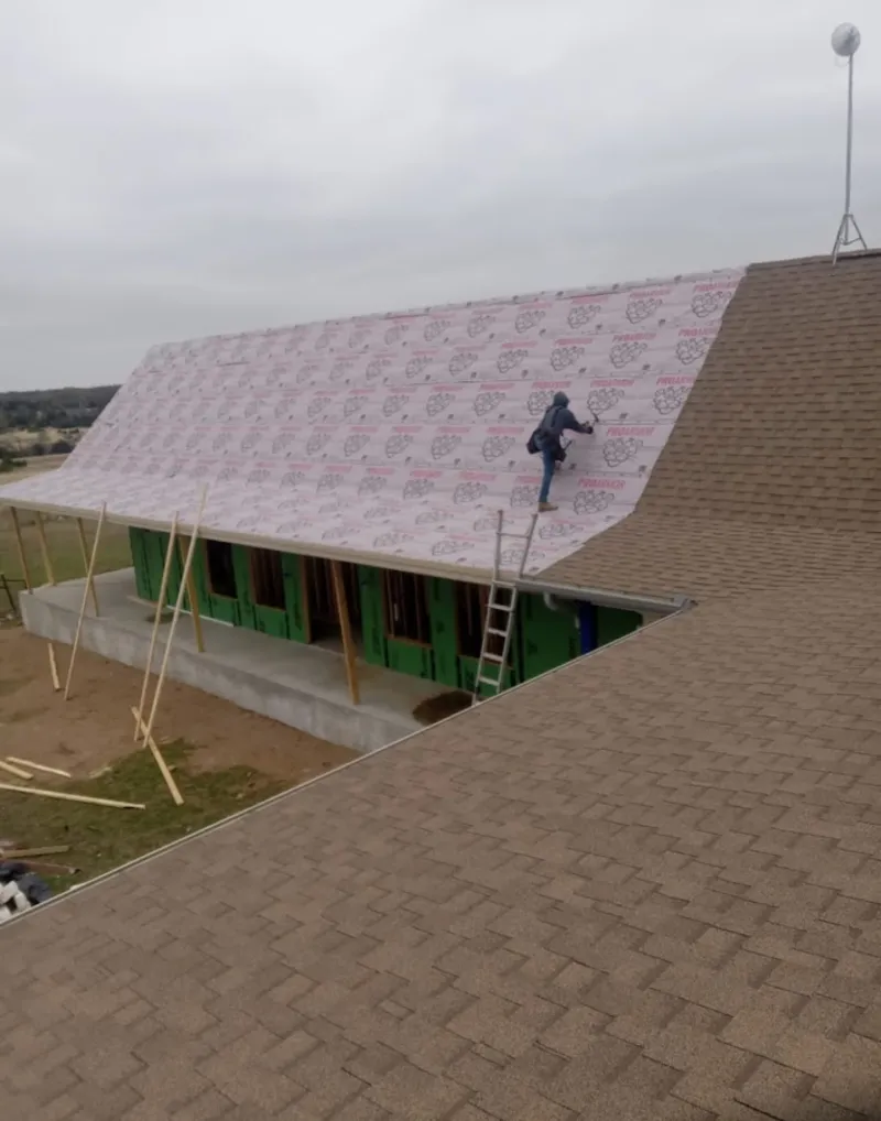 Worker preparing underlayment for a metal roof installation in Massanetta Springs